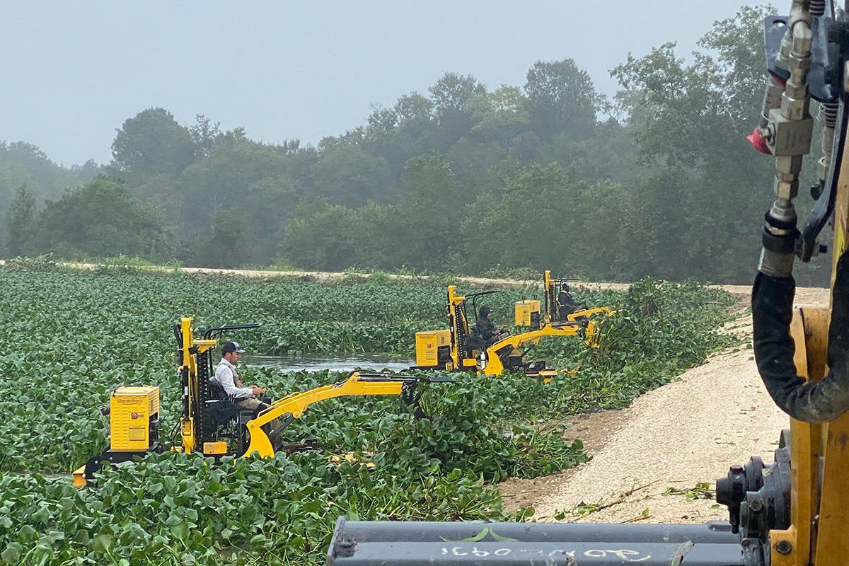 Men in aquatic weed harvesting equipment