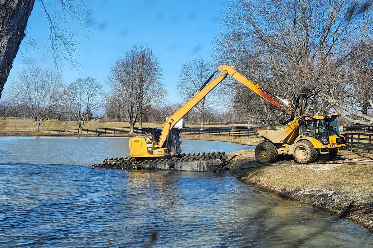 Excavator dredging in pond